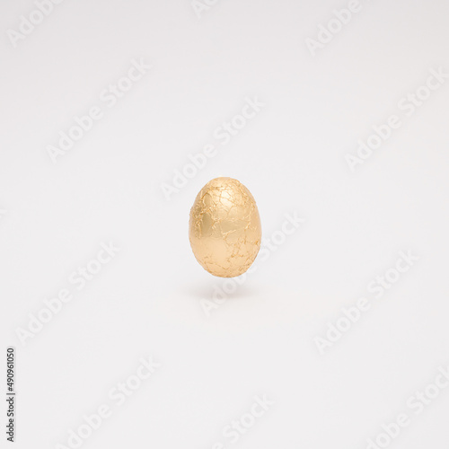 Easter creative layout made with golden Easter egg levitating on a white background. Minimal holiday still life concept.