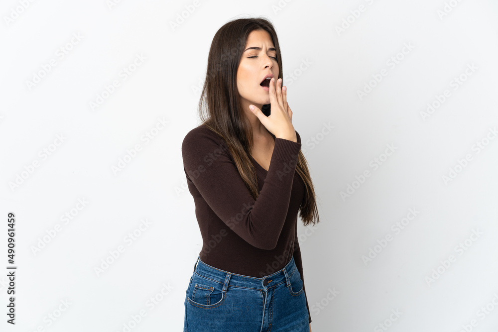 Teenager Brazilian girl isolated on white background yawning and covering wide open mouth with hand Teenager Brazilian girl isolated on white background yawning and covering wide open mouth with hand