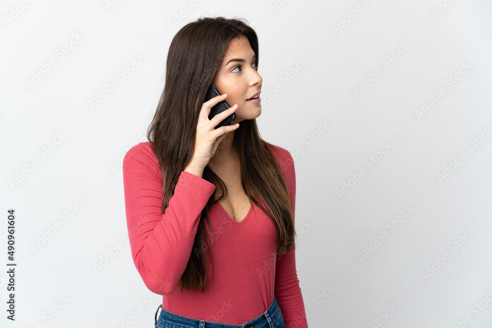 Teenager Brazilian girl isolated on white background keeping a conversation with the mobile phone with someone Teenager Brazilian girl isolated on white background keeping a conversation with the mobile phone with someone