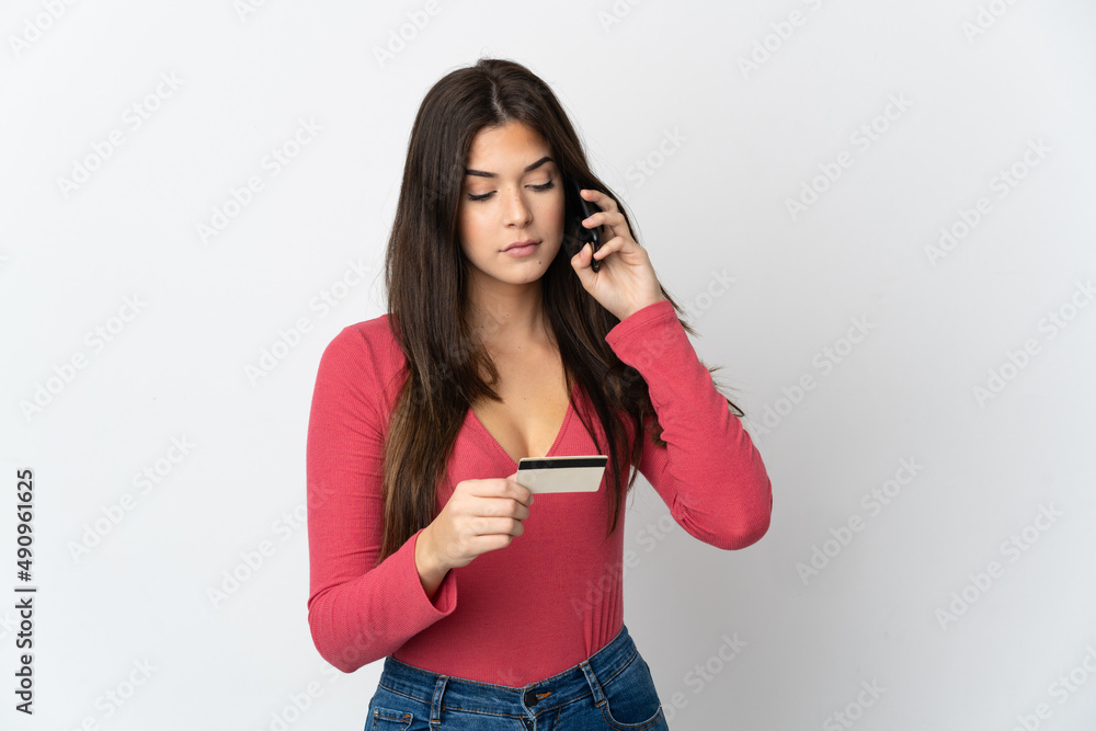 Teenager Brazilian girl isolated on white background buying with the mobile with a credit card