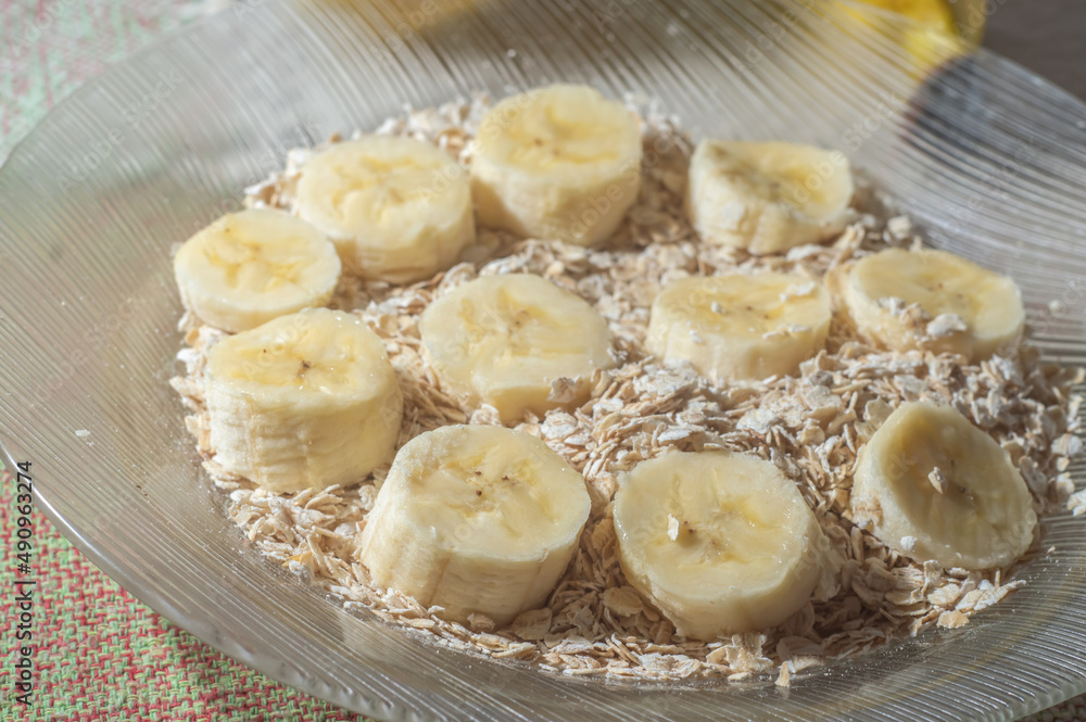 flaked oats and sliced banana, on a plate that is on a table with natural light,copy space in several parts flaked oats and sliced banana, on a plate that is on a table with natural light,copy space in several parts