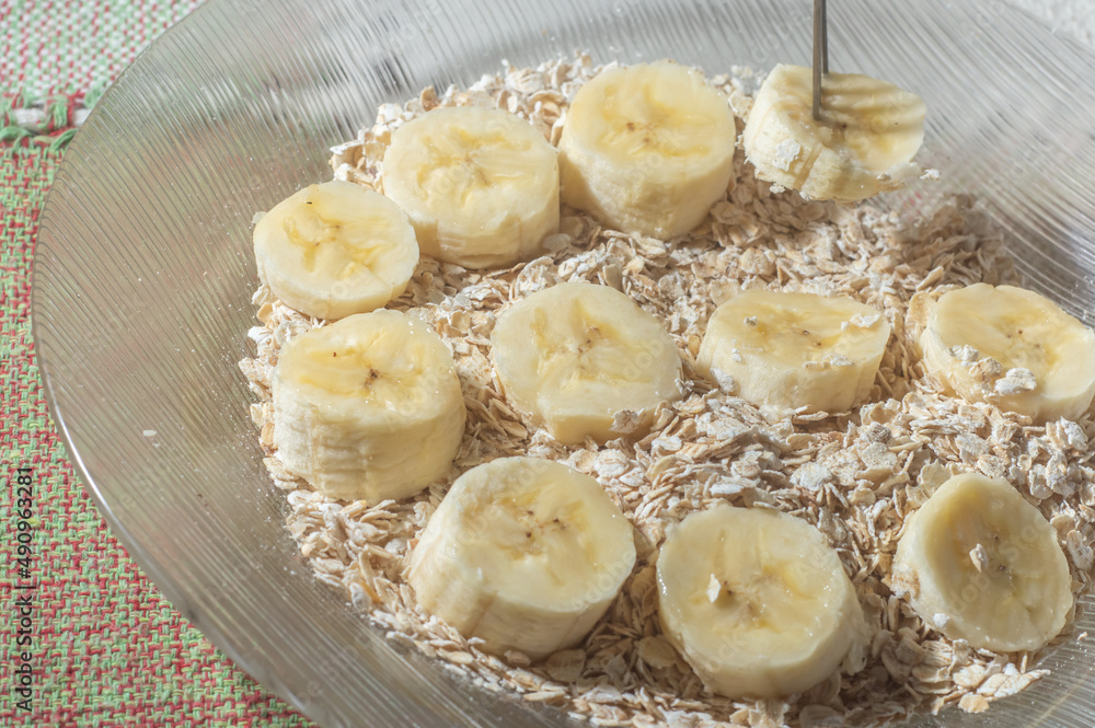 flaked oats and sliced banana, on a plate that is on a table with natural light,copy space in several parts flaked oats and sliced banana, on a plate that is on a table with natural light,copy space in several parts