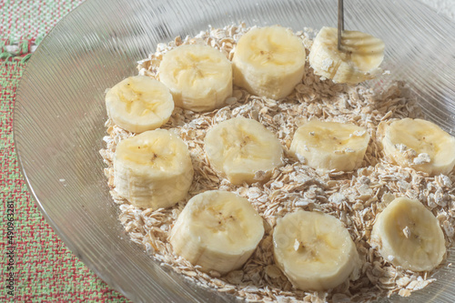 flaked oats and sliced banana, on a plate that is on a table with natural light,copy space in several parts