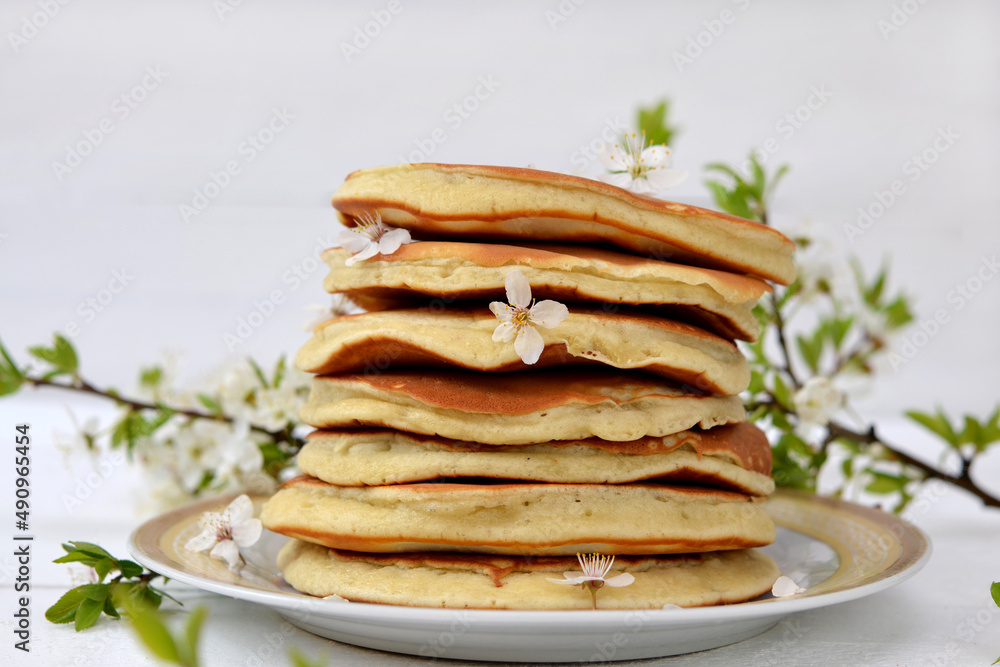 lush pancakes and plum blossom branch on the table close-up