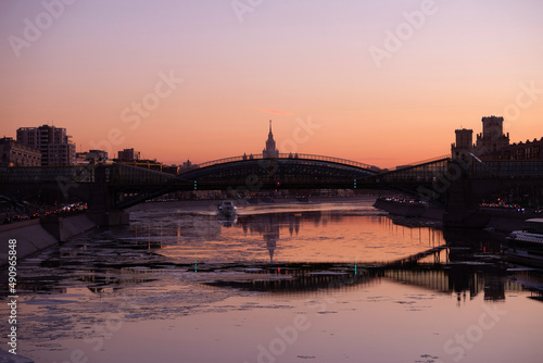 Urban landscape with beautiful red sunset on Moscow River and Moscow State University at far after the bridge