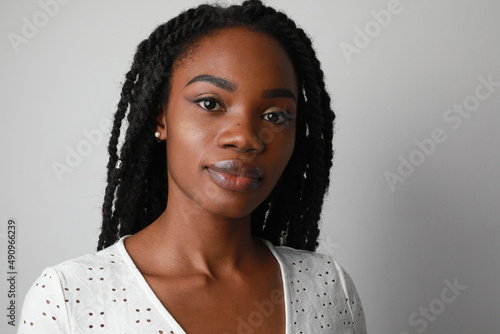 Positive and happy young African woman with long braids posing over white wall.