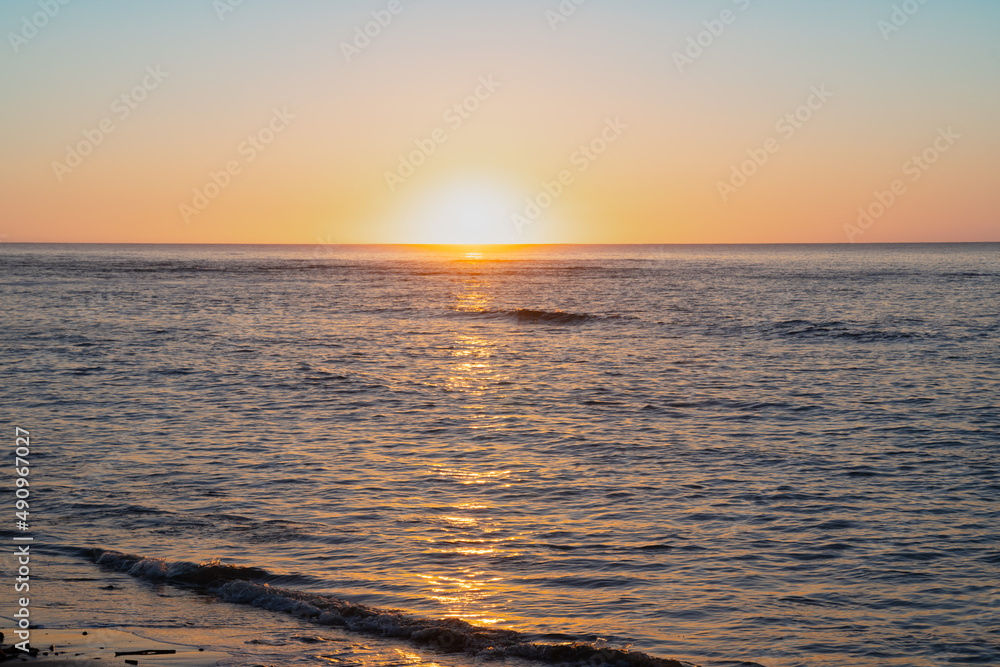Sunrise just on horizon starts to illuminate and warm the air over sea of Tokomaru Bay