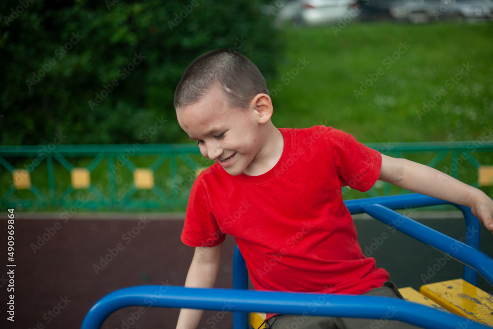 Child on merry-go-round. Boy spins on carousel for children on playground. Junior schoolboy plays alone. Child on merry-go-round. Boy spins on carousel for children on playground. Junior schoolboy plays alone.