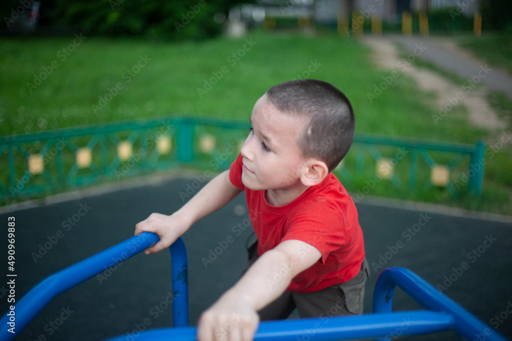 Child on merry-go-round. Boy spins on carousel for children on playground. Junior schoolboy plays alone. Child on merry-go-round. Boy spins on carousel for children on playground. Junior schoolboy plays alone.