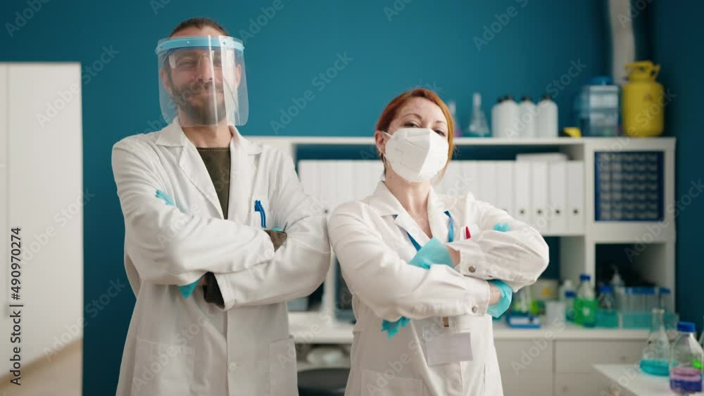 Man and woman scientists wearing medical and screen mask standing with arms crossed gesture at laboratory Man and woman scientists wearing medical and screen mask standing with arms crossed gesture at laboratory