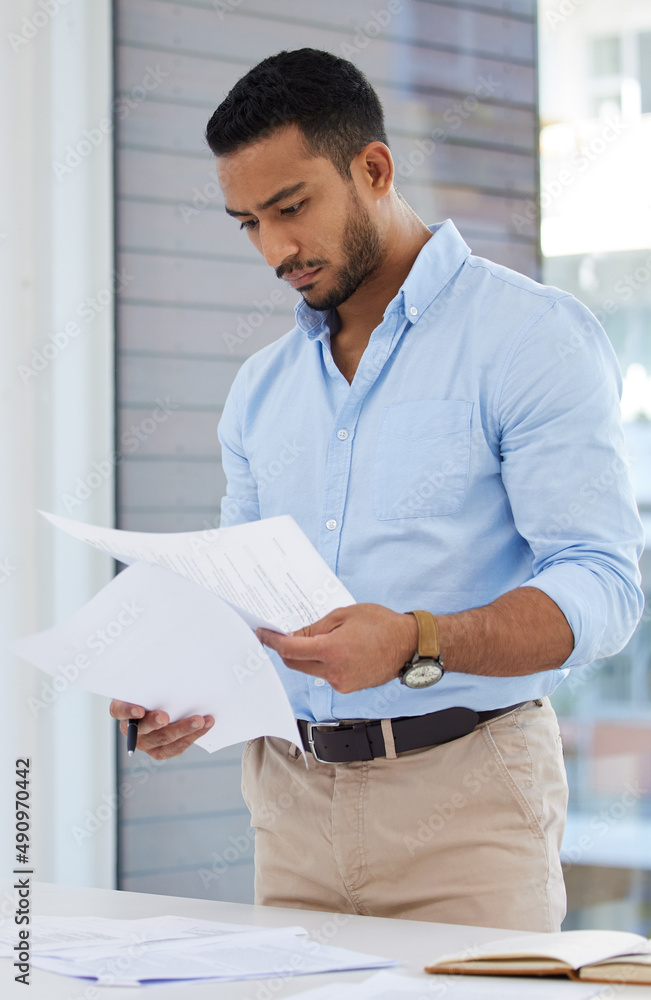 Getting his paperwork in order. Shot of a young businessman going through paperwork in an office. Getting his paperwork in order. Shot of a young businessman going through paperwork in an office.