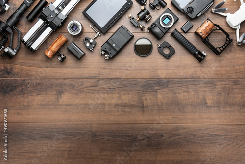 Short movie production essentials on wooden background with copy space. Different video making equipment for indie cinema production. Video production tools on brown table view from above.