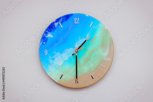 Vintage clock handcrafted from wood and epoxy resin. Clock in the form of an ocean shore and a sandy beach. Multi-colored stains of epoxy resin in the form of a finished product.