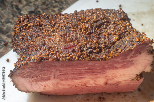 Roasted beef, pastrami on slate cutting board, male hand holding a piece of pastrami,Copy space.