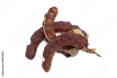 Pile of tamarind fruits on white background. Top view. Flat lay. Sticky brown acidic pulp from the pod of a tree of the pea family, widely used as a flavoring in Asian cooking.