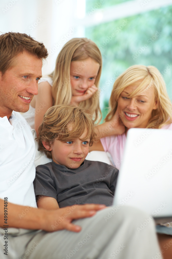 Browsing the web together. Happy young family using a laptop together on the sofa at home. Browsing the web together. Happy young family using a laptop together on the sofa at home.