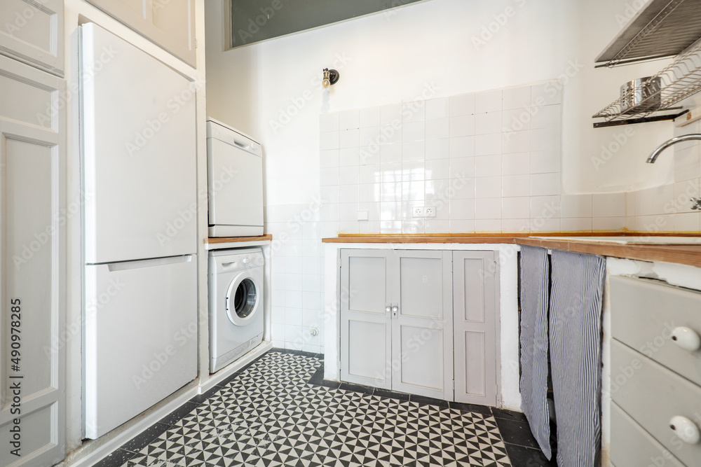 Fototapeta premium Corner of a kitchen decorated in a vintage style with built-in furniture with a brown wooden door and a used wooden countertop with white appliances