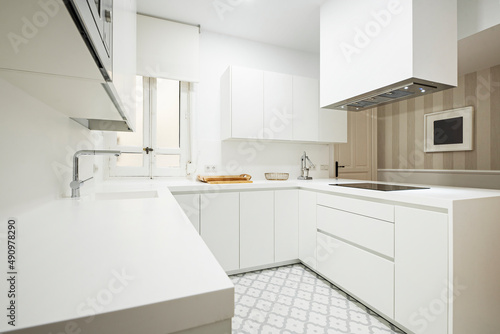 Kitchen with horseshoe-shaped furniture, with a hood on the ceiling and a one-piece worktop with hydraulic stoneware floors