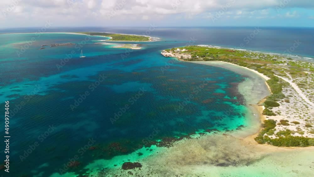 Aerial shot of remote atoll and lagoon with sailing boat Aerial shot of remote atoll and lagoon with sailing boat