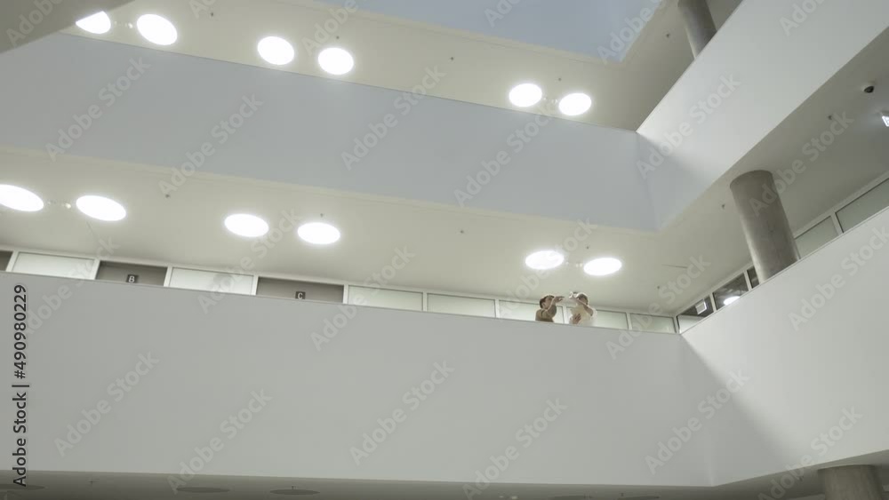 Creative People Working On Future Architecture Project.Workers standing in the balcony inside the open wide space of futuristic modern architecture building which looks like corporation headquarters. Creative People Working On Future Architecture Project.Workers standing in the balcony inside the open wide space of futuristic modern architecture building which looks like corporation headquarters.
