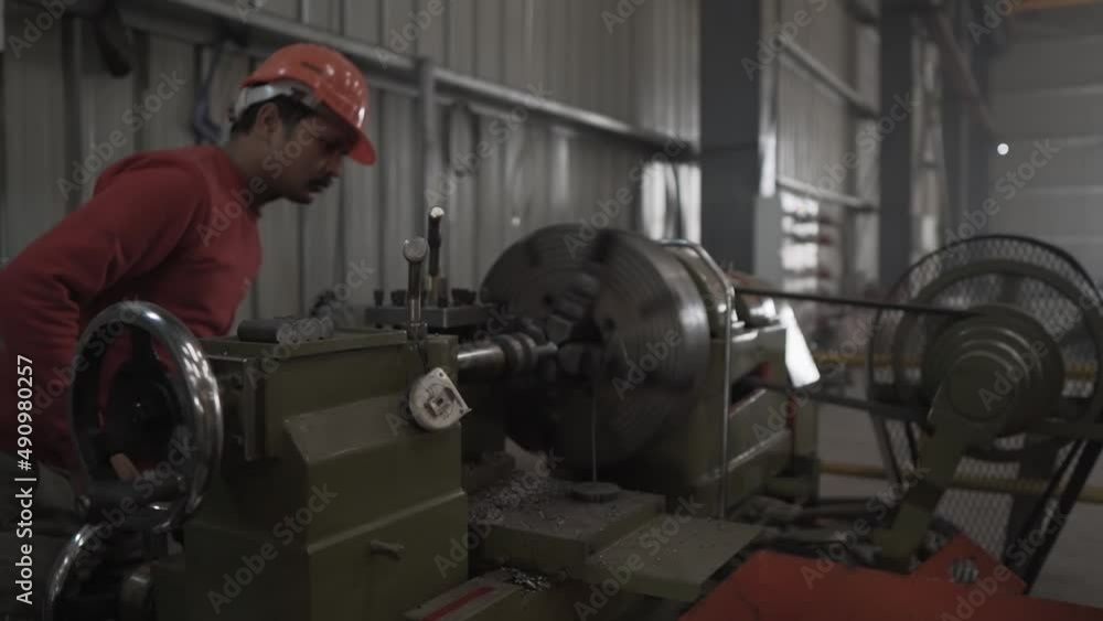 Indian Factory worker is programming a CNC machine, technician wearing helmet working in mechanical manufactory production line in Asia Indian Factory worker is programming a CNC machine, technician wearing helmet working in mechanical manufactory production line in Asia