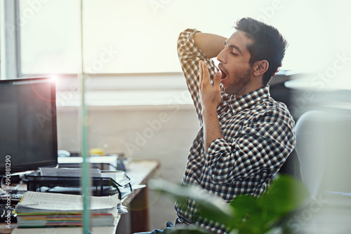 Works really taking its toll. Cropped shot of a businessman yawning while working at his desk. photo
