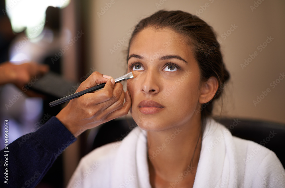 Makeover time. Shot of an attractive young woman having makeup applied to her face.