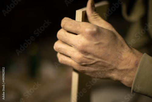 Carpenter holds tree. Worker chooses board. Details of carpentry workshop. © Олег Копьёв