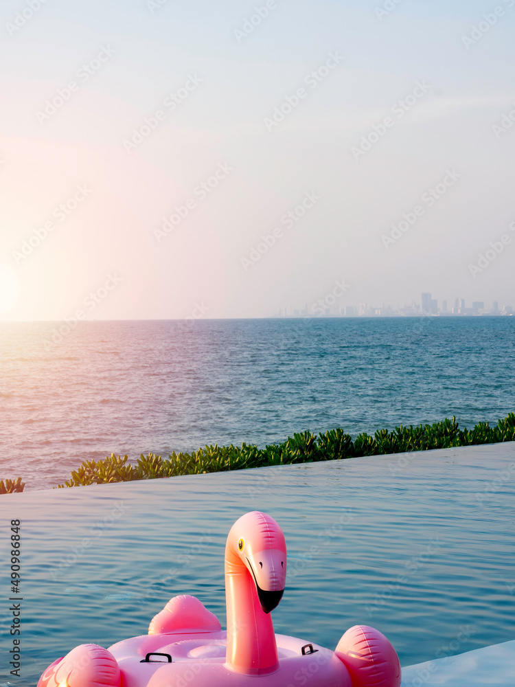 Face of lonely pink flamingo, inflatable ring in the swimming pool on sea and blue sky background with copy space, vertical style. Flamingo swim ring for summer vacation. Face of lonely pink flamingo, inflatable ring in the swimming pool on sea and blue sky background with copy space, vertical style. Flamingo swim ring for summer vacation.