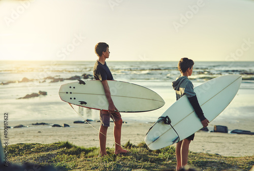 Theyve got a case of surfing fever. Shot of two young brothers holding their surfboards while looking towards the ocean.