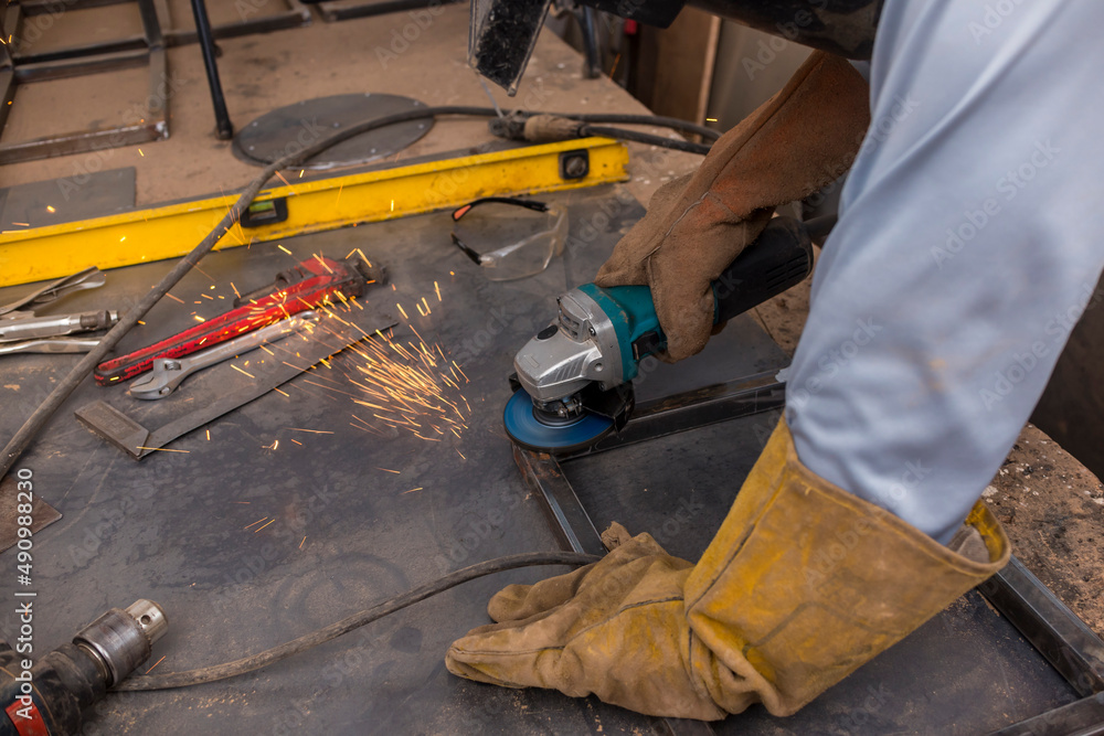 Foto de Using an angle grinder to smooth a welded corner joint for a