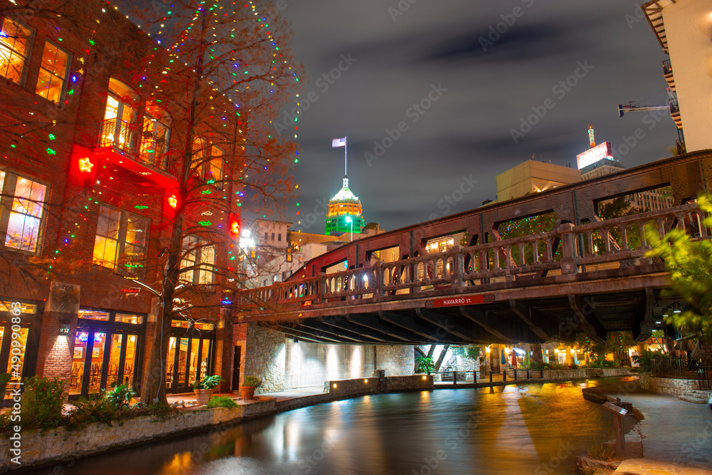 San Antonio River Walk at Navarro Street bridge with Tower Life building at the background at night in downtown San Antonio, Texas, USA.