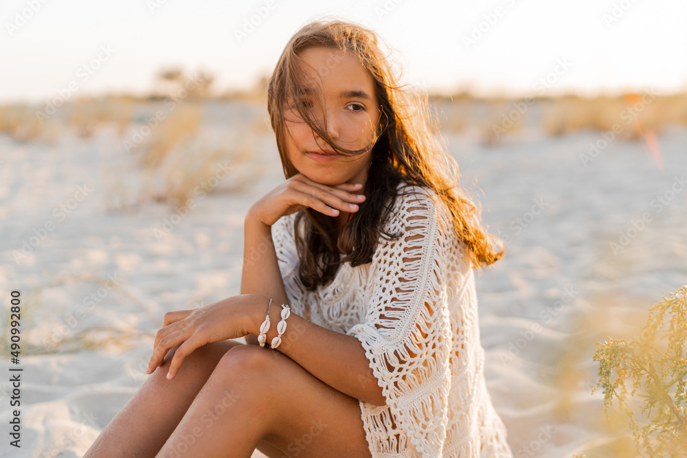 Summer photo of small girl in stylish boho outfit posing on the beach. Warm sunset colors. Wacation and travel concept. Summer photo of small girl in stylish boho outfit posing on the beach. Warm sunset colors. Wacation and travel concept.