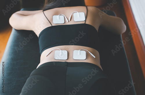 Physical therapy for woman patient with TENS electrode pads on back,Preparing equipment photo