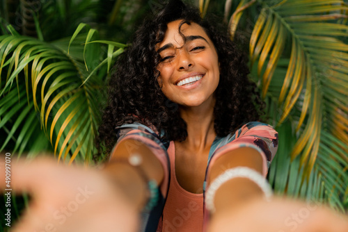 Billede på lærred Outdoor  portrait of smiling lovely woman with curly hairs posing over tropical trees and palm leaves