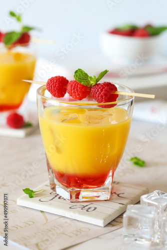 Orange and raspberry cocktail with mint, ice and fresh raspberries on a table