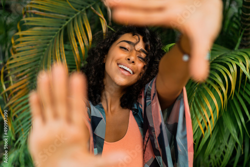 Canvas Print Outdoor  portrait of blissful  lovely woman with curly hairs posing over tropical trees and palm leaves