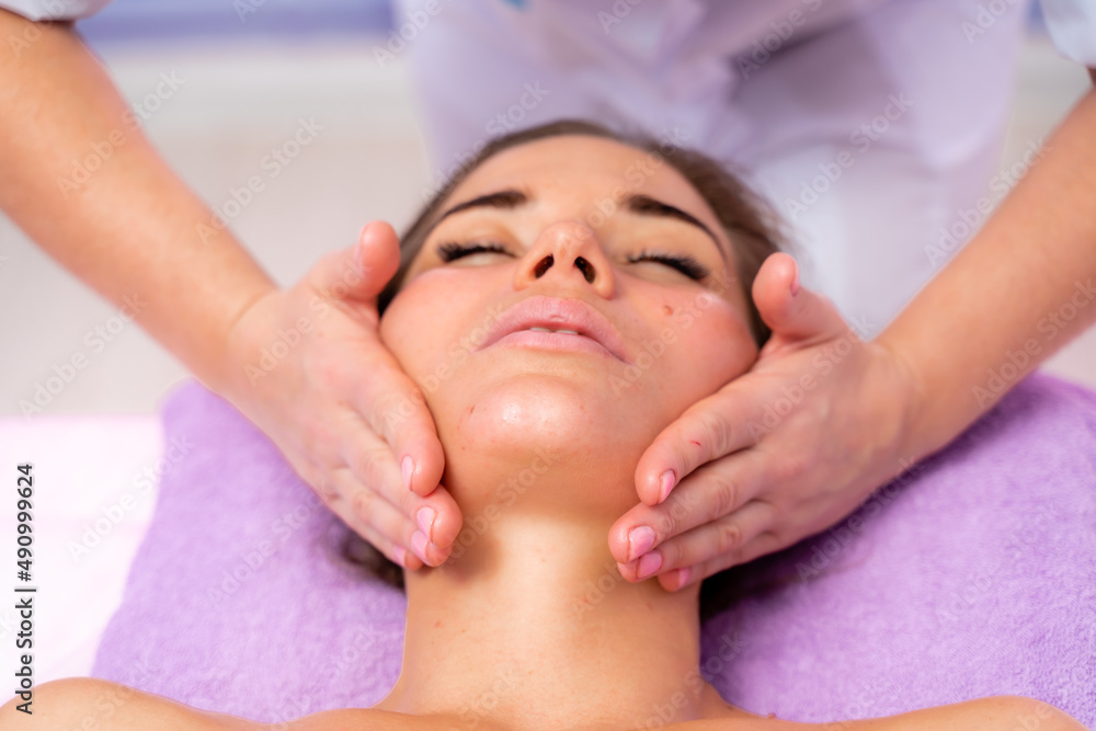 Relaxing massage. European woman getting facial massage in spa salon, side view Relaxing massage. European woman getting facial massage in spa salon, side view