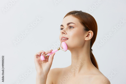 Wallpaper Mural portrait woman jade face massager wrinkle smoothing smile light background Torontodigital.ca