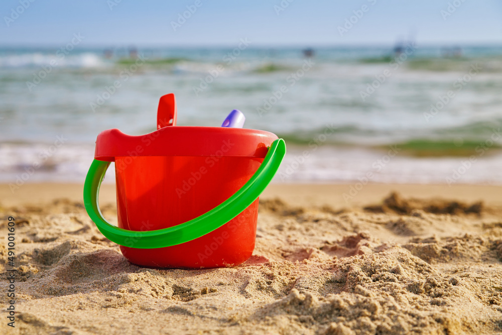 Red children's bucket in the sand on the seashore Red children's bucket in the sand on the seashore
