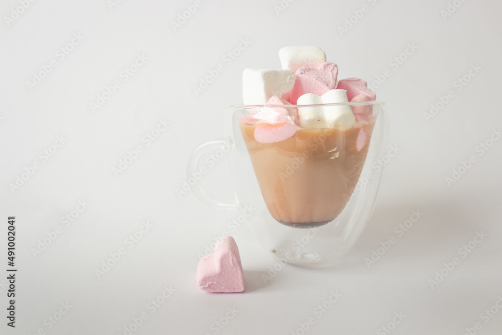 Glass double bottom cup of coffee with marshmallow in heart form. Isolated on white background.