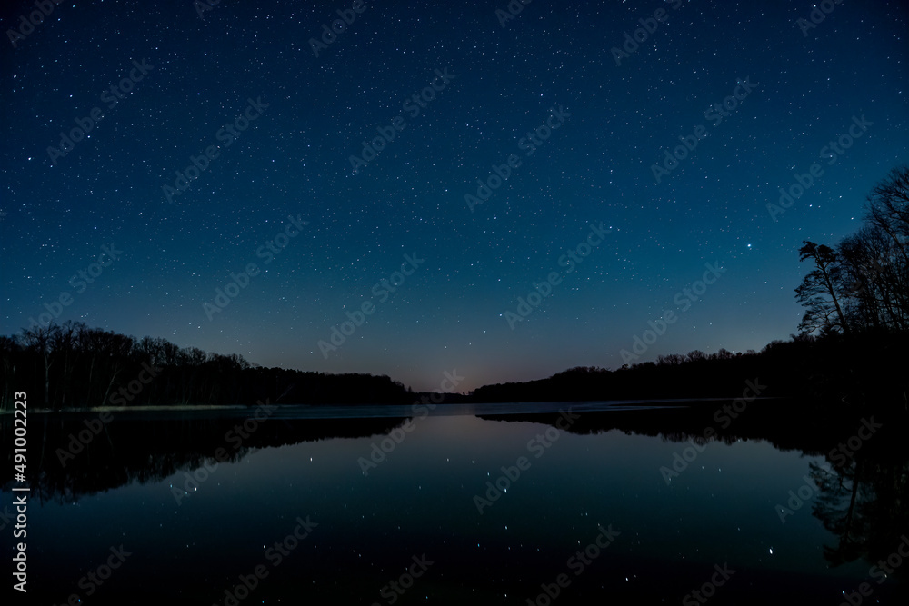 Nocne niebo nad jeziorem. Widok odbijających się gwiazd w lustrze wody. - obrazy, fototapety, plakaty 