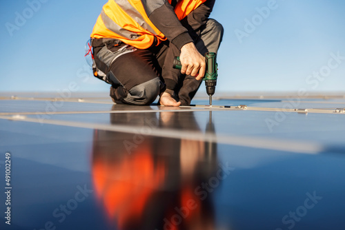 Cropped picture of a worker installing solar panels on the roof.