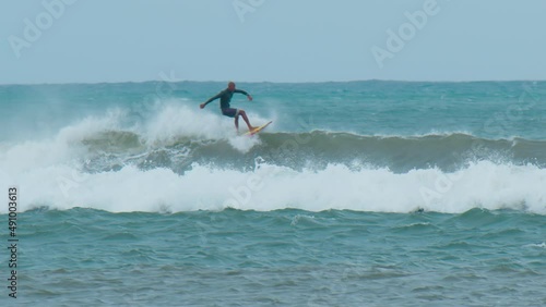 Young man with long hair rides the ocean wave at the Mauritius surf spot