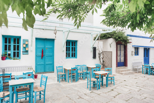 Beautiful traditional greek street with flowers and cafe tables on Amorgos island, Greece