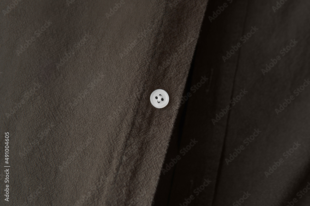 Close up White buttons sew on clothes unisex dark brown tone color shirt. minimalist style everyday outfit looks concept
Close up White buttons sew on clothes unisex dark brown tone color shirt. minimalist style everyday outfit looks concept