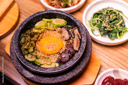 Bibimbap in a black heated stone bowl, Korean traditional dish- bibimbap mixed rice with vegetables Include beef and fried egg, Japanese hot pot food