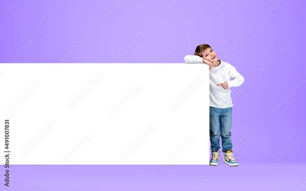 Kid smiling and point at mockup poster on bright background Kid smiling and point at mockup poster on bright background
