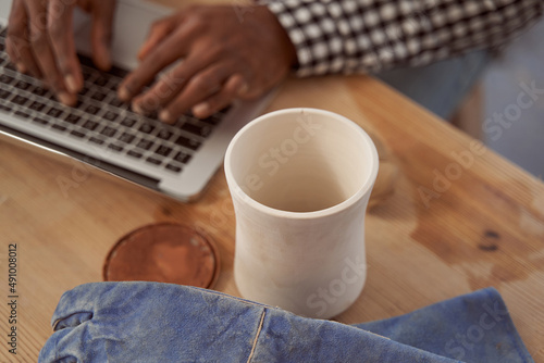 Ceramist seated at table typing on laptop photo