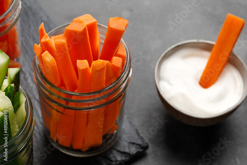 Fotografia Dipping yogurt sauce and carrot sticks in glass jar. Healthy food